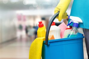 Cleaning lady with a bucket and cleaning products on blurred background.